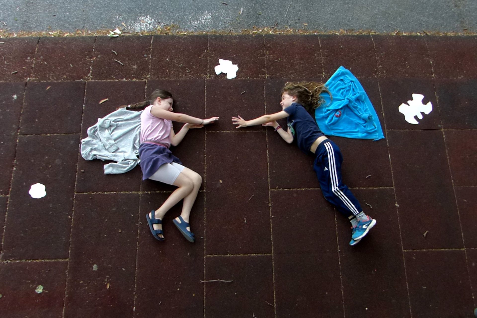 Zwei Mädchenauf dem Boden liegnd mit Flügeln, Arme zu einander streckend